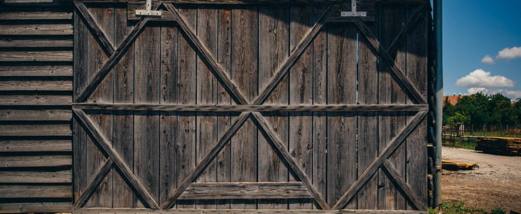 Weathered wooden barn door with diagonal cross-bracing in a rustic outdoor setting