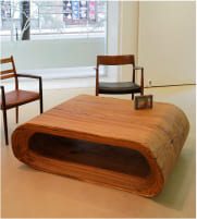 OZE luxury wooden coffee table with integrated shelf displayed in a white gallery space alongside vintage chairs