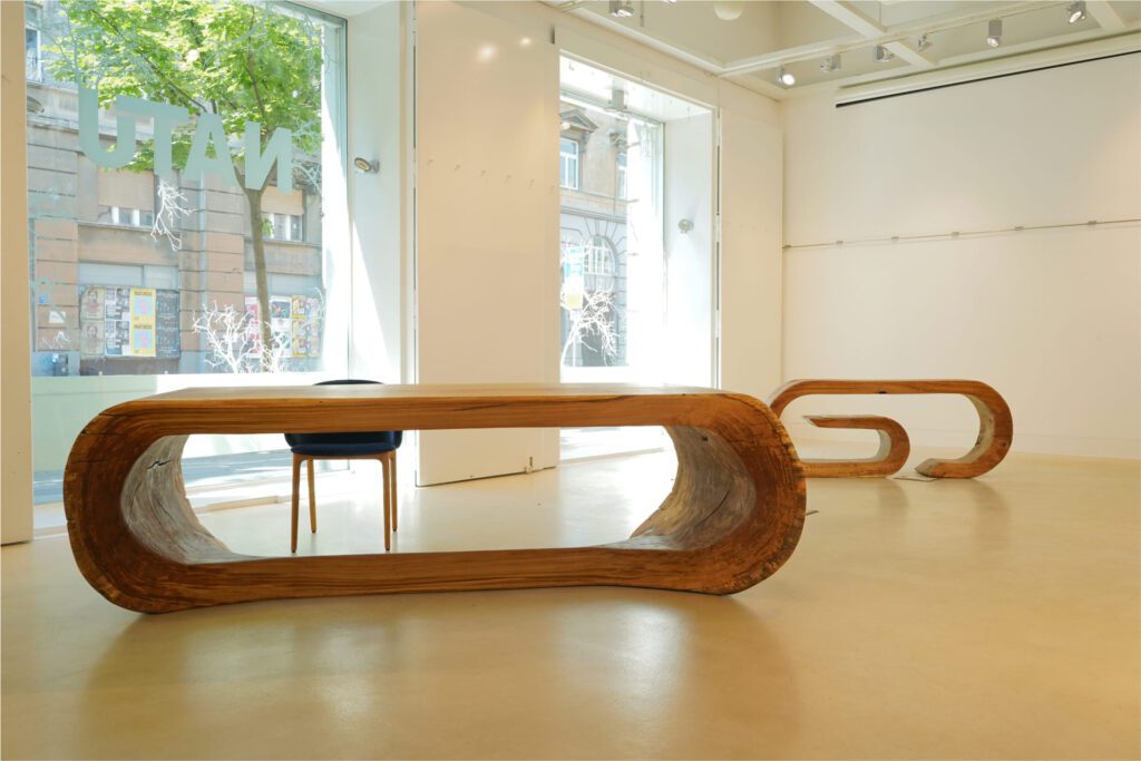 OZE sculptural wooden table and commode displayed in a bright white gallery space